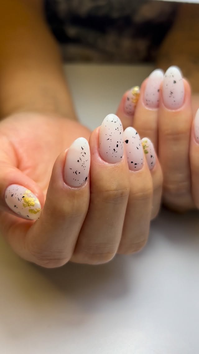 Uñas almendra blancas con acabado speckle y láminas de oro